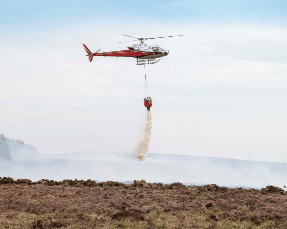 Helicopter dropping water repeatedly on reignited hotspots